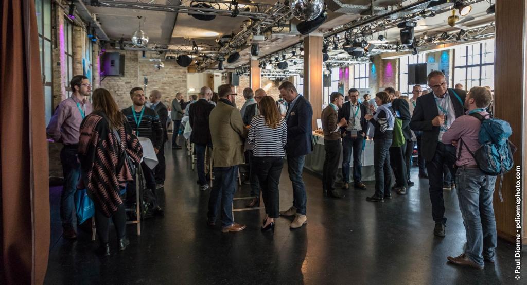 A room filled with people, standing in groups and talking.