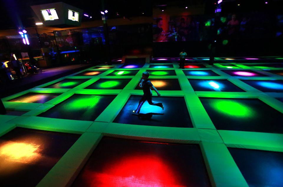 Glowi9ng lights on main court of trampoline park with a running boy.