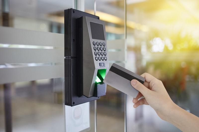 A hand uses a security card on a locked keypad.
