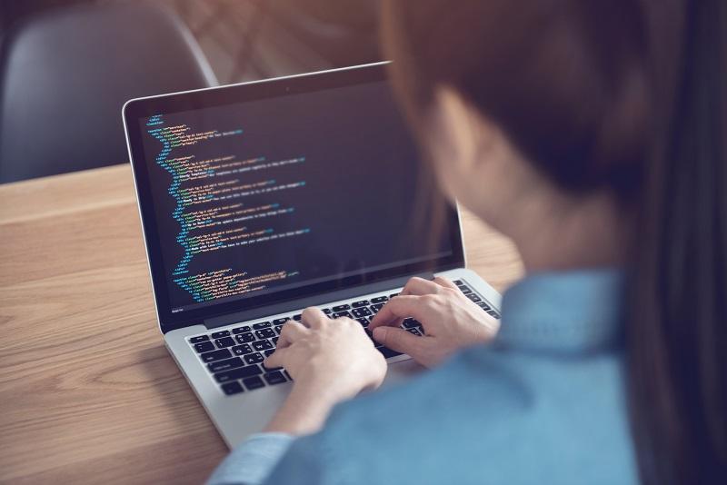 A woman using her laptop, working on coding.