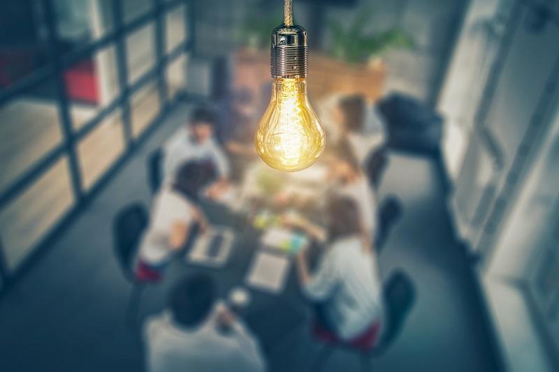 A lightbulb hovering above workers at an office table.