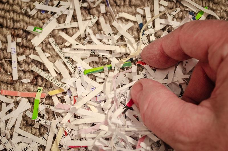 A hand picking from a stack of shredded paper.