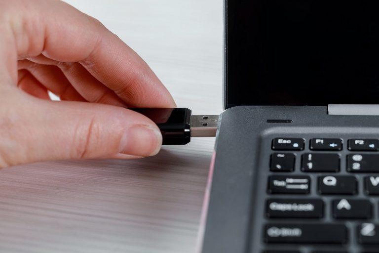 Eine Hand schließt ein Speicherlaufwerk an einen Laptop an.