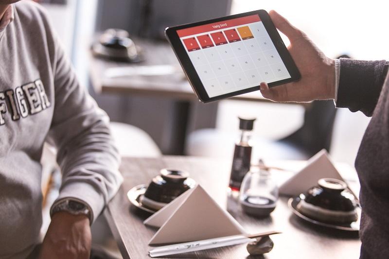 A person holding a tablet for another person.