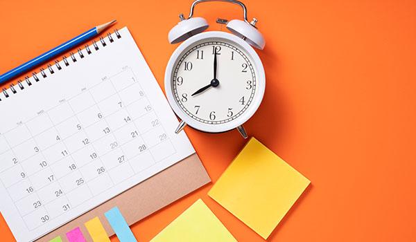 An alarm clock next to a calendar.
