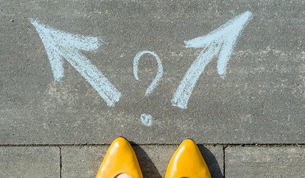 A person deciding which way to walk, guided by arrows written in chalk.