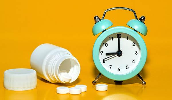 Pills next to an alarm clock.