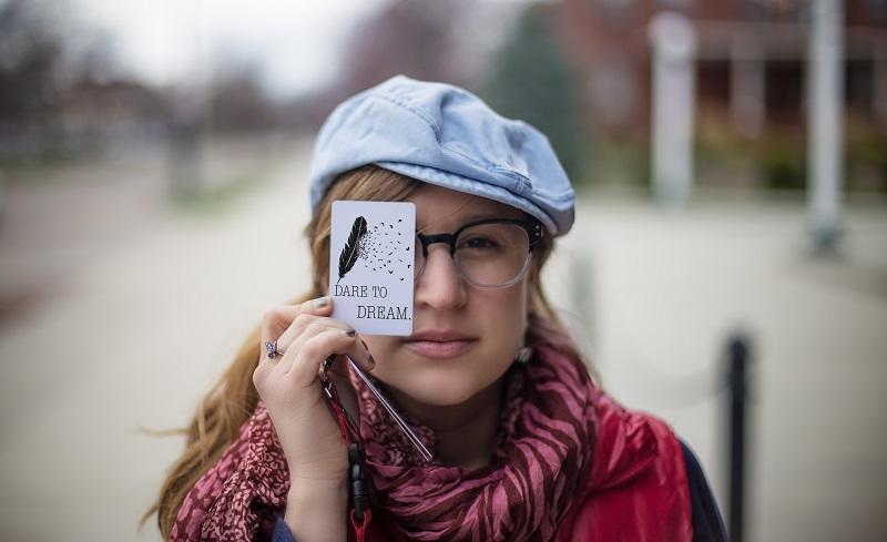 A woman holds a card in front of her eye.