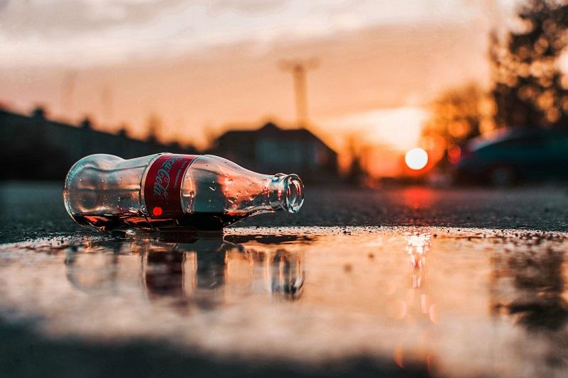 A Coke bottle in a puddle.