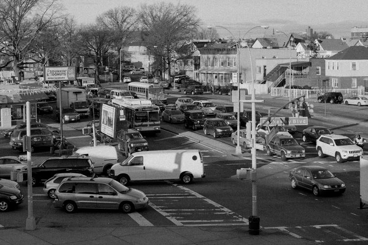 A photograph of a street corner busy with traffic. 