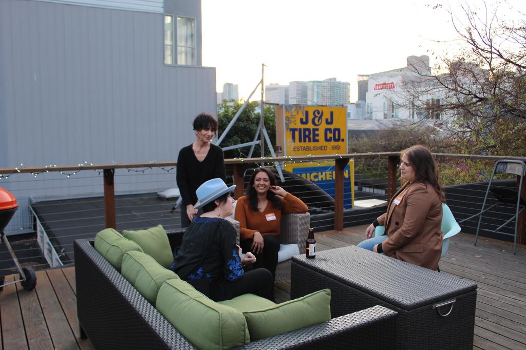 people in a conversation sitting on a rooftop terrance.