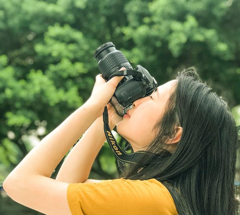 A young woman uses a Nikon camera.