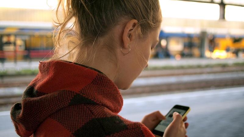 A young woman uses a mobile device outdoors.