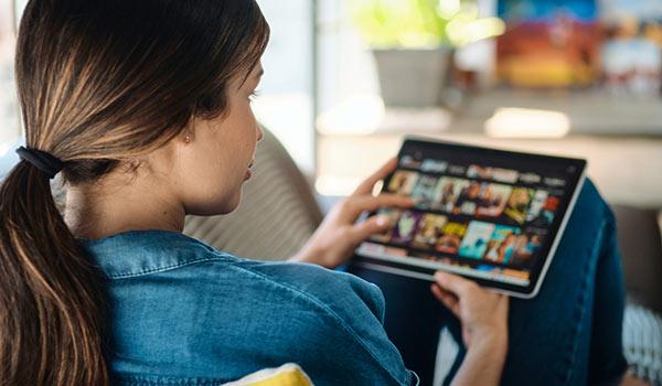 Eine Person leiht sich über ein Tablet einen Film aus.