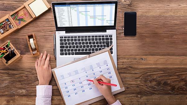 A person creating a schedule on a calendar.