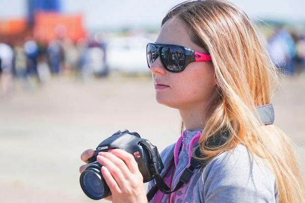 Eine junge Fotografin steht an einem Strand.
