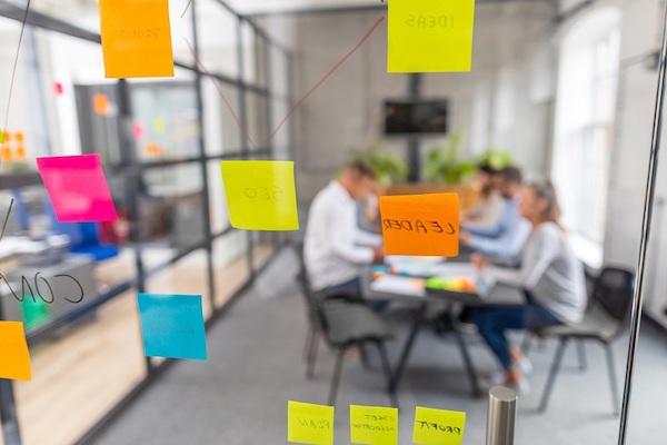 Eine Gruppe von Mitarbeitern bei der Arbeit, betrachtet durch eine transparente Wand.