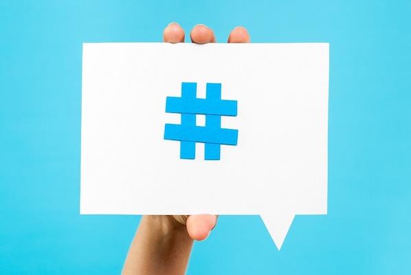 Abbildung einer Hand, die eine Karte mit einem Hashtag-Symbol von Twitter hochhält.