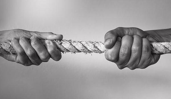 Two people tugging on each side of a rope.