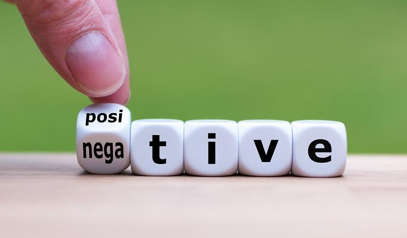 A hand turning a dice from 'positive' to 'negative'.