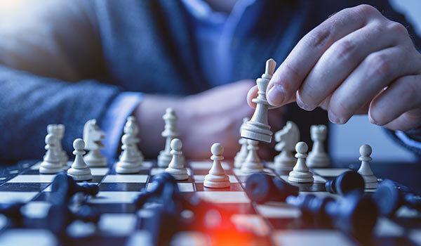 A hand moving chess pieces.