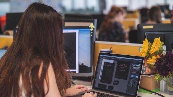 Eine Frau arbeitet auf ihrem Laptop an verschiedenen Designs.