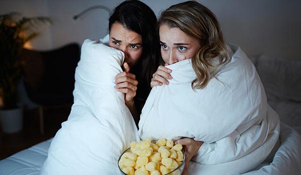 Zwei Frauen sehen sich einen Gruselfilm an.