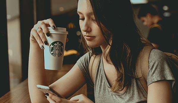 Eine junge Frau trinkt einen Kaffee von Starbucks.
