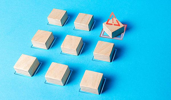 In einer ordentlichen Matrix gestapelte Holzklötze, bei denen einer abweicht, symbolisch für die Notwendigkeit der Einhaltung von Metadaten-Standards.