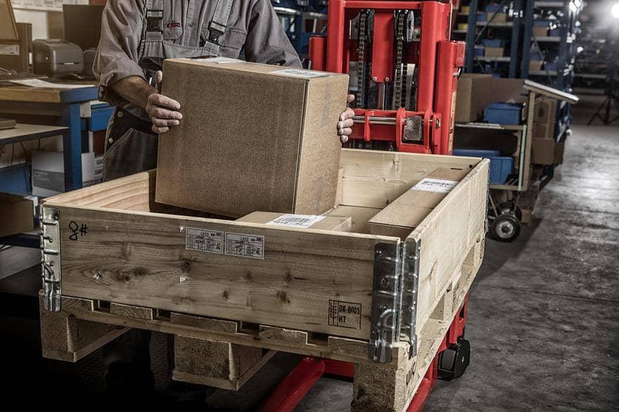 Screenshot of a Logitrans asset in Canto, showing a person loading a plywood cart with cardboard boxes in a warehouse.