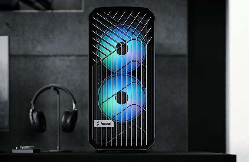 Fractal Design desktop tower on a desk displayed against a black background with a set of black over-ear headphones slightly to the left displayed.