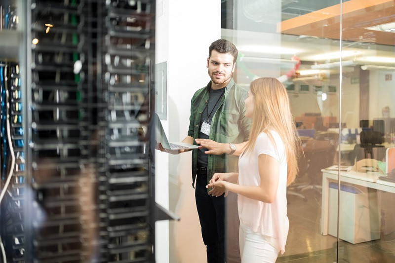 Ein Kollege und eine Kollegin überprüfen einen Datenserver.