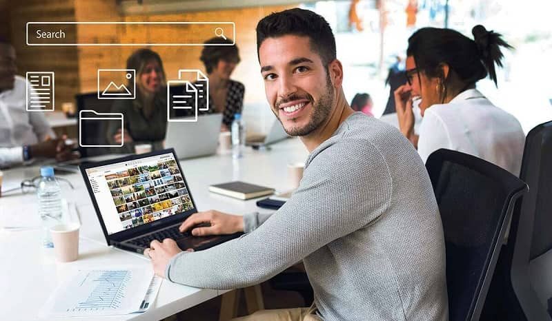 Ein Mann in einem grauen Pullover verwendet Canto auf seinem Laptop während einer Besprechung.