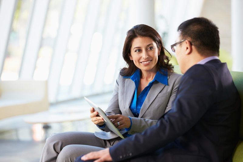 Zwei Mitarbeiter sitzen zusammen und unterhalten sich über die Inhalte von Content Marketing mithilfe eines Tablets.