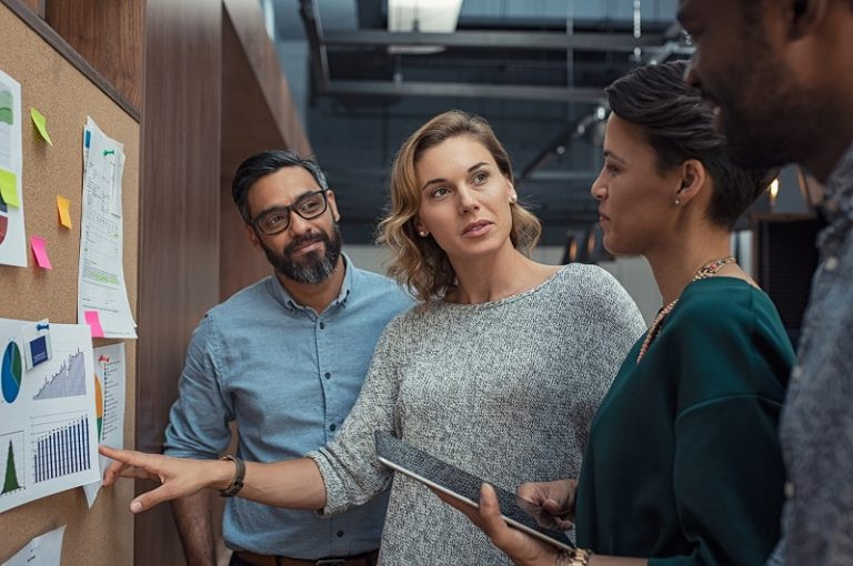 Eine Gruppe von Mitarbeitern diskutiert vor einer Pinnwand über das Thema Enterprise Content Management.
