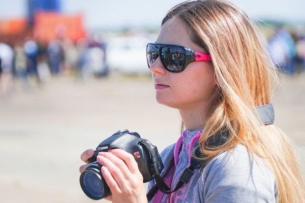 Eine junge Fotografin steht an einem Strand.