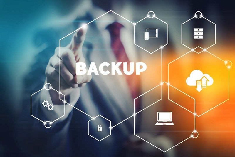 Eine Person berührt ein Diagramm, das mit dem Wort "Backup" beschriftet ist, und um das Symbole für Cloud-Speicher, Dateisicherheit und Computergeräte angeordnet sind.
