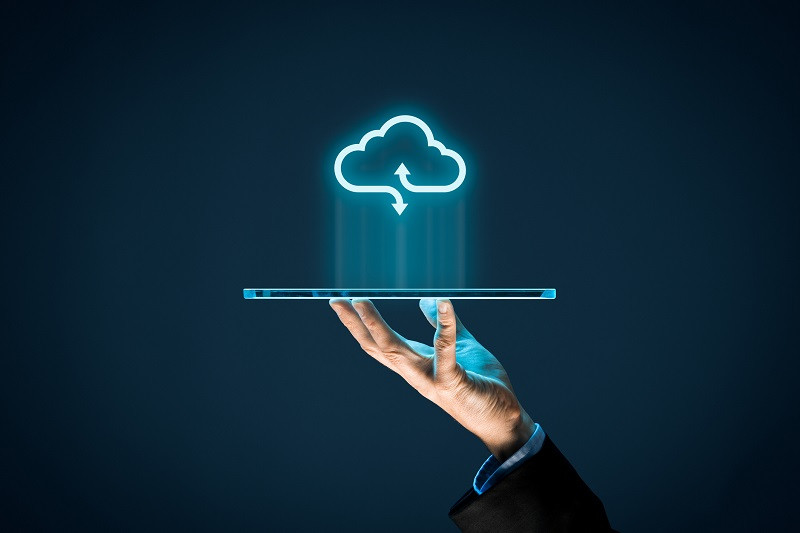 Eine Hand hält ein mobiles Gerät, über dem eine digitale Wolke dargestellt ist.