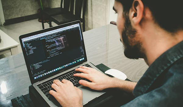 Ein Mann programmiert auf einem Laptop.