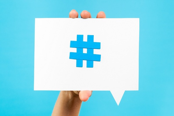 Abbildung einer Hand, die eine Karte mit einem Hashtag-Symbol von Twitter hochhält.