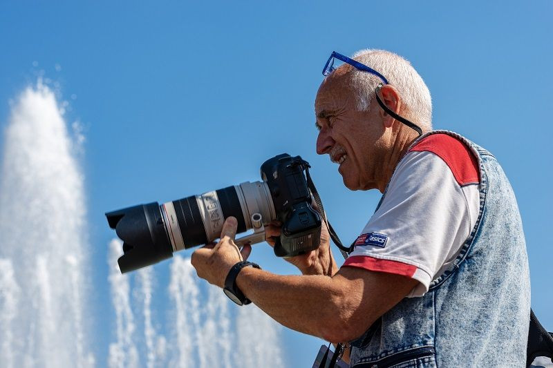 Abbildung eines männlichen Fotografen mit einer Kamera in der Hand.