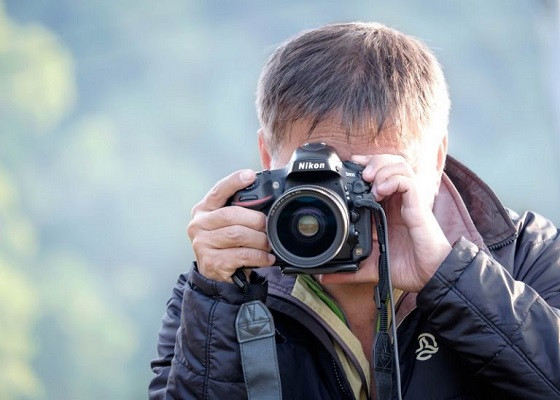 Ein Mann macht mit einer Kamera von Nikon ein Foto.