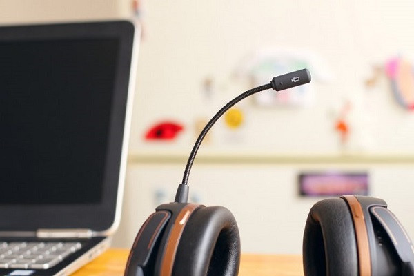Auf einem Tisch neben einem Computer liegt ein unbenutztes Headset.