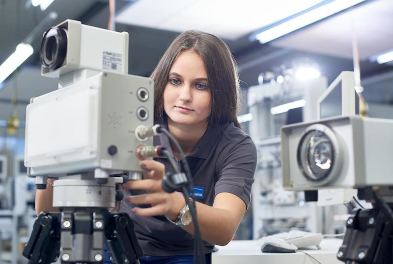 Eine Technikerin justiert ein Gerät in der Produktion.