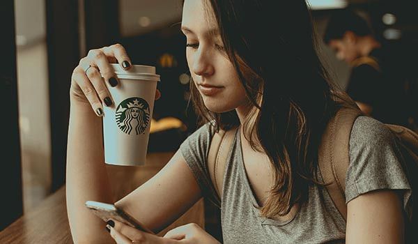 Eine junge Frau trinkt einen Kaffee von Starbucks.