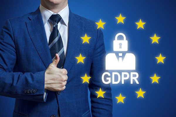 Ein Mann steht neben einem Symbol für die europäische Datenschutzverordnung und gibt seine Zustimmung per Daumen-Hoch-Geste.