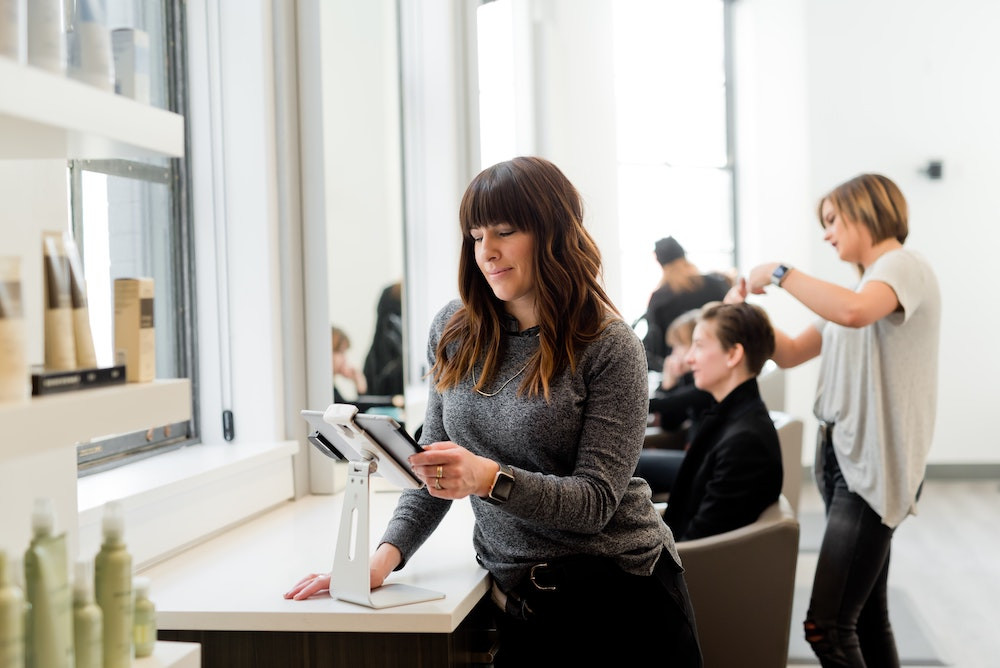 Eine Frau in einem Friseursalon schaut auf ein Tablet.