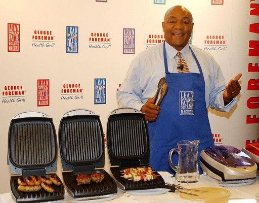 Ein Bild von George Foreman neben seinem Markenzeichen, dem Grill.