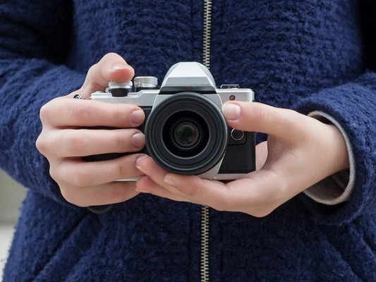 Eine Frau hält eine klassische Olympus-Kamera in der Hand und möchte wahrscheinlich bald ORF in AI konvertieren.