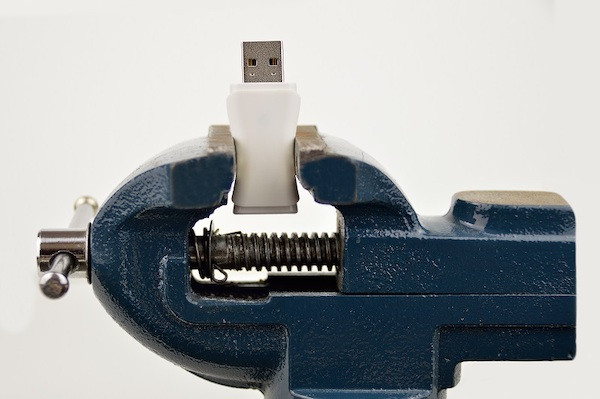 Ein USB-Stick in einem Schraubstock, symbolisch für ein Binary Large Object.